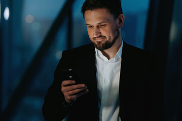 Businessman use smart phone at night in office. A man with a phone in his hands