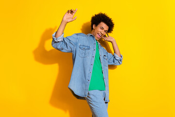 Photo of nice young man dancing wear denim shirt isolated on yellow color background