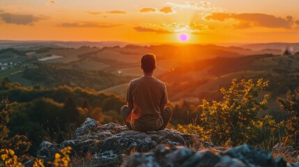 Obraz premium A man is sitting on a rock and looking at the sun
