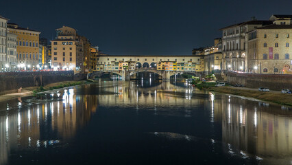 Obraz premium Famous Ponte Vecchio bridge timelapse over the Arno river in Florence, Italy, lit up at night