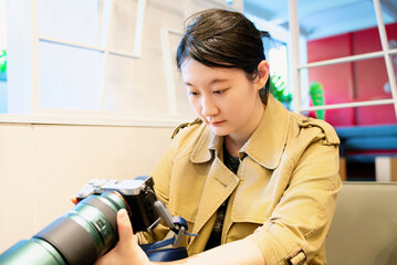 Young Photographer Adjusting Lens in Cafe Setting