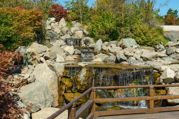 Triple waterfall splits into three streams in Japanese garden. Public landscape park of Krasnodar or Galitsky Park, Russia.