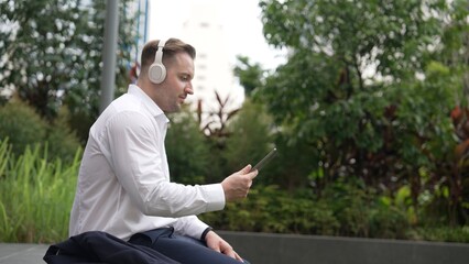 Businessman wear his headphone to listen relaxed music while take off suit and move to music at...