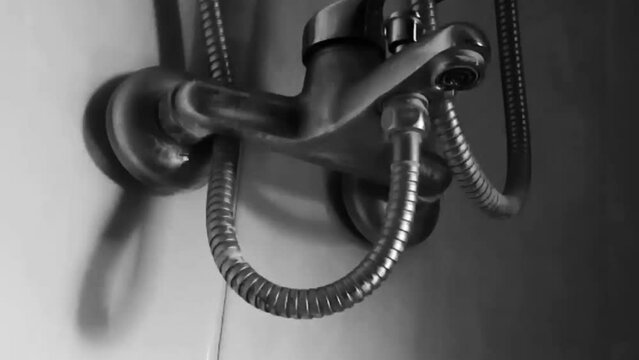 black and white shot of water dripping from the tap