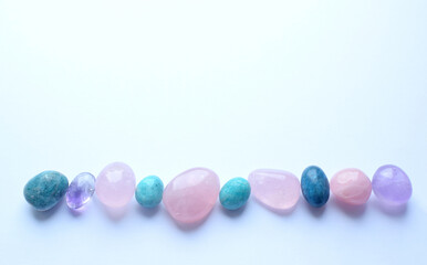 Multi-colored semi-precious round stones of rose quartz, kyanite and amazonite on a white...