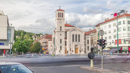 Naklejka premium City traffic and people on the cross walk in front of Saint Joseph's Church on Titova street timelapse hyperlapse in Sarajevo, Bosnia