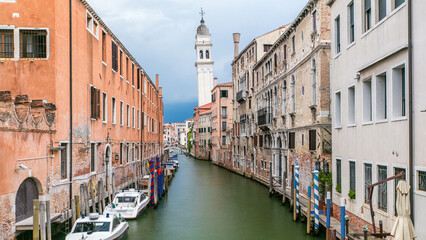 A view of Venice timelapse: canal, bridge, boats and an old tower in the background