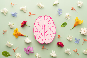 Flat layout of human brain anatomy with colorful fresh flower on green background. Mental health...