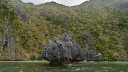 Picturesque, bizarre karst rocks rise above the turquoise bay. Lush tropical vegetation on the...