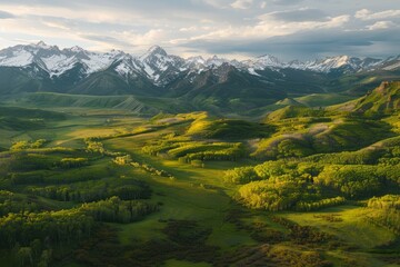 Aerial view of expansive green valley with towering mountains in distance