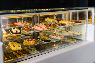 Showcase with sweets, Various desserts and cakes for sale in the pastry shop. Glass display at store bakery pastry shop.