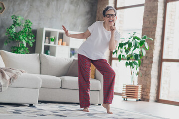 Full length photo of lovely mature lady dance sing karaoke dressed white garment modern living room...