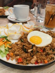 a plate of traditional fried rice with chicken, and sunny side up egg served with pickles and crackers