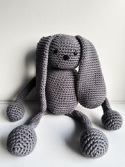 Knitted hare toy sitting on a white background.
