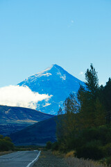 Fototapeta premium Lanin volcano surrounded by clouds, clear summit in sight and ice glaciers, between Argentina and Chile, Lanin National Park