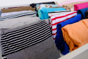 bunch of colorful clothes, woman is cleaning out her wardrobe, Vertical storage of clothing in...