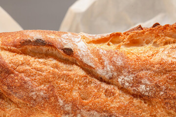 Detail of baguette bread.  Freshly baked loaf of bread on crumpled parchment paper. Shallow depth of field