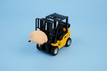 Forklift truck carrying human brain on blue background