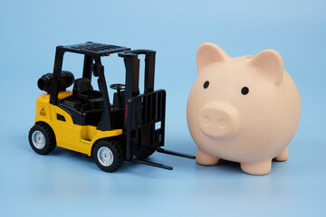 Forklift truck and piggy bank on blue background. Cost of shipping, storage and logistics concept.