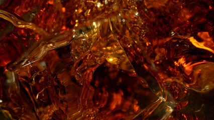Closeup of ice cube inside glass of whiskey.