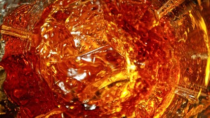 Closeup of ice cube inside glass of whiskey.