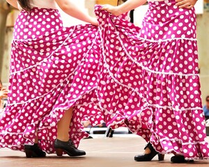 A couple of flamenco dancers in pink polka dots skirts with ruffles and frills performing Sevillanas, a typical Spanish flamenco dance