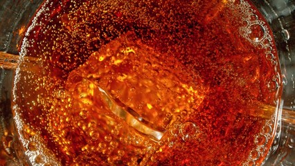 Closeup of ice cube inside glass of cola.