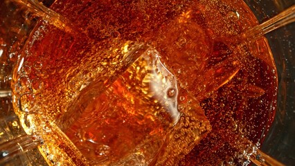 Closeup of ice cube inside glass of cola.