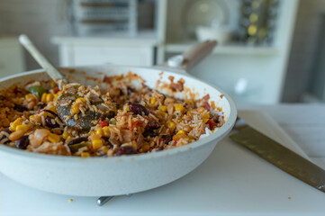 Healthy rice dish with ham, kidney beans, corn, peppers, onions, tomatoes and herbs. Low fat and high protein dinner or luch in a frying pan