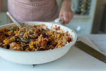 Woman in the kitchen with a fresh cooked healthy rice bean dish