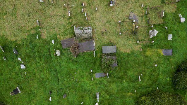 Drone shot flying over a very old Irish graveyard with gravestones.