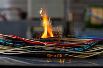 Flames, sparks, smoke between electrical cables, closeup. Short circuit in the twisted wires from...