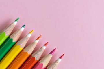 Pencils of different sharpened colors, together on a pale pink background