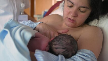 Mother breastfeeds newborn baby for the first time at hospital clinic, authentic real life mom feeding her infant in the first minutes of life, maternal care and growth