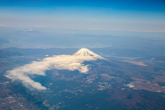 Mount Fuji seen from an airplane on a beautiful blue day with snow on the peak.