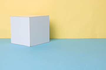 White wooden cube on a yellow and blue background.
