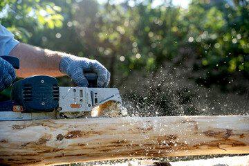 a carpenter works with an electric pipe on a sunny day