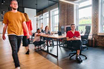 A diverse group of business professionals collaborates in a modern startup coworking center, utilizing a mix of paper-based and technological tools such as mobile phones and computers 