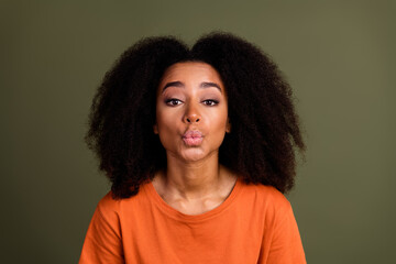 Portrait of gorgeous african girl with wavy hairstyle wear orange t-shirt send air kiss pouted lips...