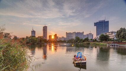 Fototapeta premium Sunset over Vienna international center skyscrapers with Kaiserwasser lake reflection view timelapse
