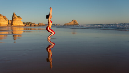 woman doing yoga chair pose on beach