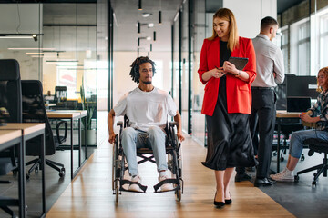 A business leader with her colleague, an African-American businessman who is a disabled person,...