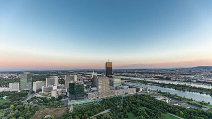 Aerial panoramic view over Vienna city with skyscrapers, historic buildings and a riverside promenade day to night timelapse in Austria.