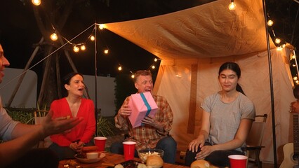 Family together celebrate anniversary in garden. Senior give gift to granddaughter. Outdoor camping...