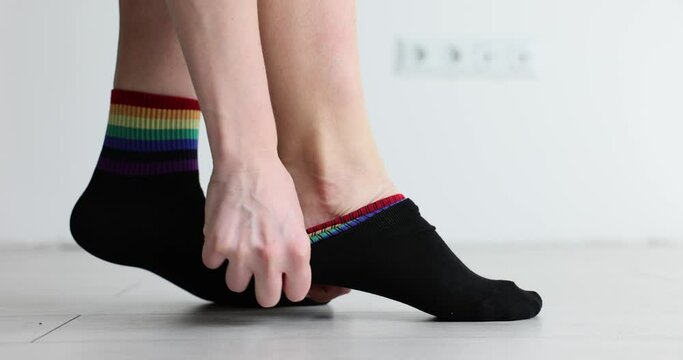 Woman puts on black socks with LGBT symbols. Fashion brands use LGBT colors in clothing