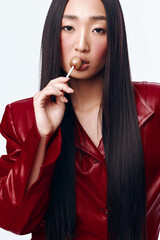 Stylish woman with long black hair in red leather jacket holding toothbrush
