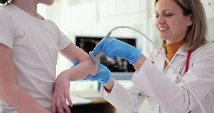 Traumatologist conducts ultrasound examination of child elbows in clinic. Bruised elbow in child signs symptoms and treatment
