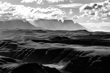Dramatic black and white view of the mountains and valleys of the Drakensberg mountains with some of the iconic peaks and cliffs rising in the background - Powered by Adobe