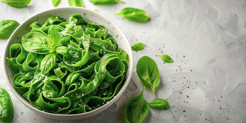 Obraz premium Bowl of alternative green spinach or pea fettuccine pasta noodles with fresh basil leaves. Option for for use: culinary recepies , healthy eating, fitness, diets. Copy space