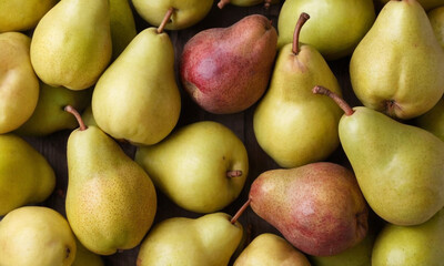 Various apples and pears tightly packed together, with both green and red apples and green pears visible, all having their stems intact.